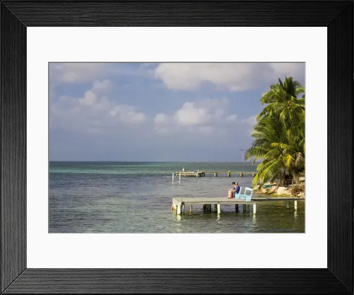 Framed Print : Belize, Tobaco Caye, Tourists sitting on pier reading Framed Print : Belize, Tobaco Caye, Tourists sitting on pier reading