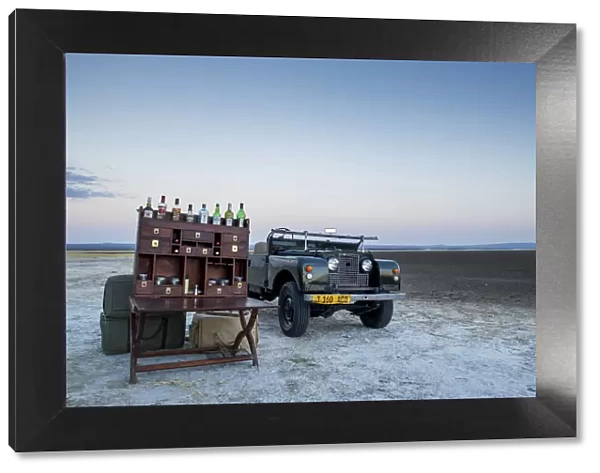 Ancient landrover and sundowner table on salt pan