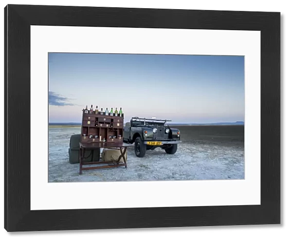 Ancient landrover and sundowner table on salt pan