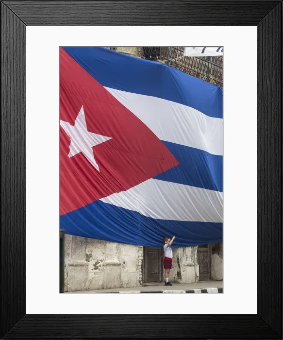 Framed Print : Cuba, Boy saluting to Huge Cuban flag hanging across buildings in a street in Santa Clara Framed Print : Cuba, Boy saluting to Huge Cuban flag hanging across buildings in a street in Santa Clara