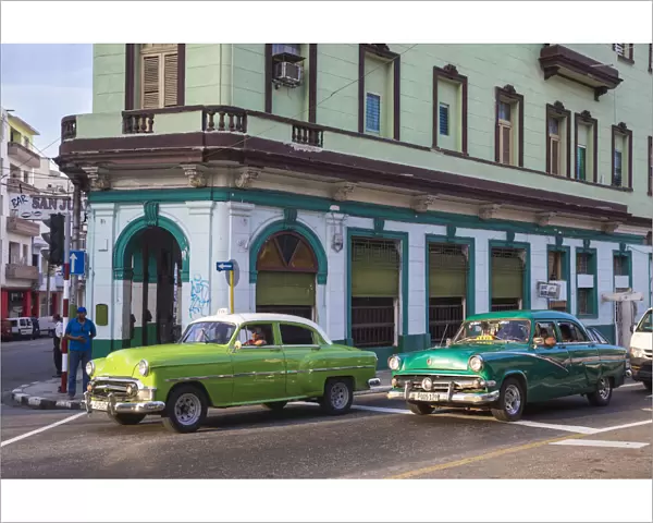 Cuba, Havana, Classic American cars passing by Bar San Juan
