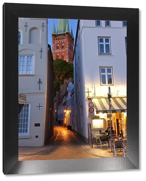 Narrow street to St Petri Church & cafe restaurant at dusk, Lubeck, Germany