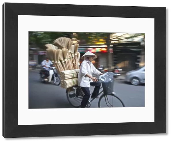 Woman carrying brooms on her bike, Old Quarter, Hanoi, Vietnam