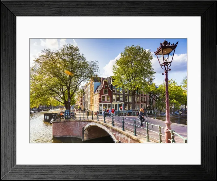 Framed Print : A woman riding a bike on a bridge over a canal in Amsterdam, Holland / Netherlands Framed Print : A woman riding a bike on a bridge over a canal in Amsterdam, Holland / Netherlands