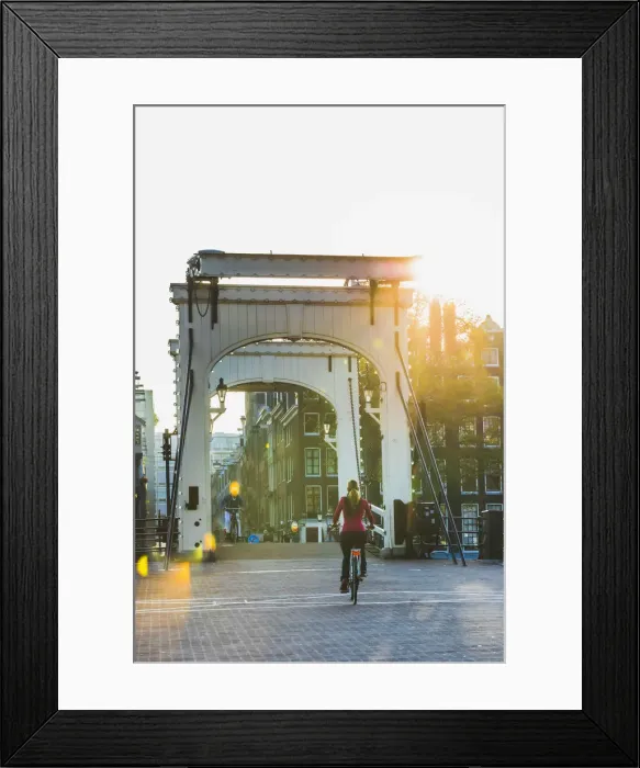 Framed Print : A woman riding a bike on a bridge over Amsterdam Canal, Holland / Netherlands Framed Print : A woman riding a bike on a bridge over Amsterdam Canal, Holland / Netherlands