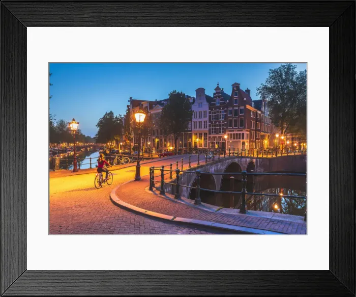 Framed Print : A woman riding a bike by night in Amsterdam along Keizersgracht canal in Amsterdam Framed Print : A woman riding a bike by night in Amsterdam along Keizersgracht canal in Amsterdam