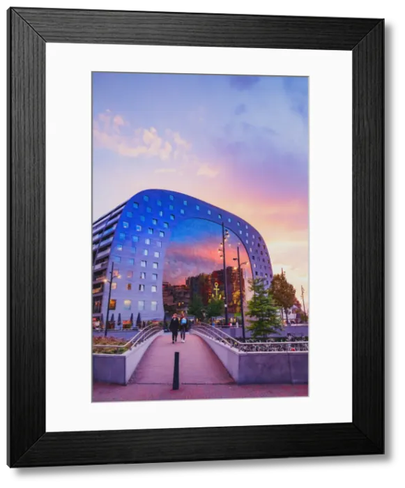 Framed Print : A couple crossing a bridge, at sunset in front of the Market Hall in Rotterdam on a