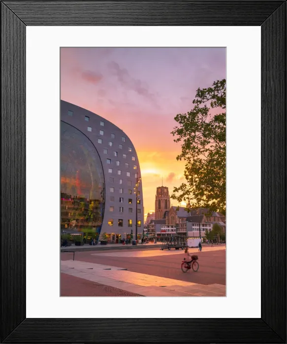 Framed Print : A woman riding a bike at sunset in front of the Market Hall in Rotterdam on a summer Framed Print : A woman riding a bike at sunset in front of the Market Hall in Rotterdam on a summer