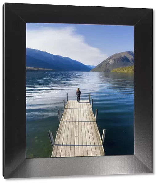 A woman standing on the wooden jetty and enjoying the view of the Rotoiti lake