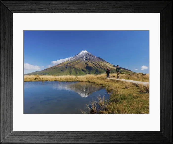 Framed Print : Two tourists hiking at Taranaki volcano in New Zealand northern island reflecting in a