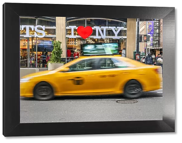 I Love New York gift shop sign and blurred yellow taxi cab passing, Times Square