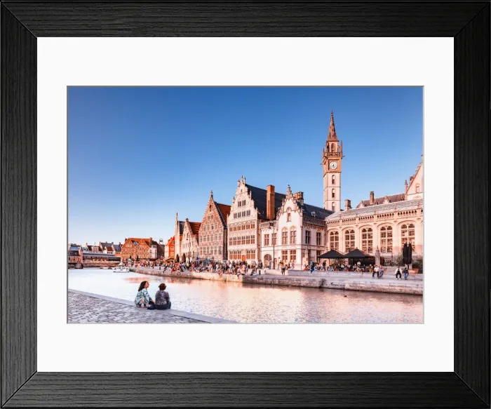 Framed Print : A couple of persons sitting by the water canal with Ghent waterfront building at sunset Framed Print : A couple of persons sitting by the water canal with Ghent waterfront building at sunset