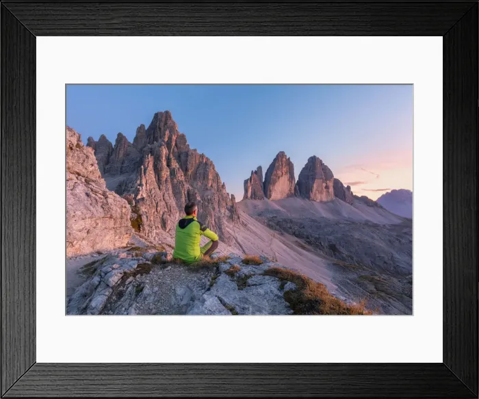 Framed Print : man sitting on the edge of the rocks admires the tre cime di lavaredo at sunset, Bolzano