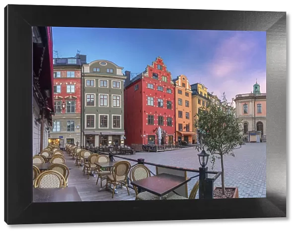 Sunrise over colorful townhouses and restaurants in the medieval Stortorget Square
