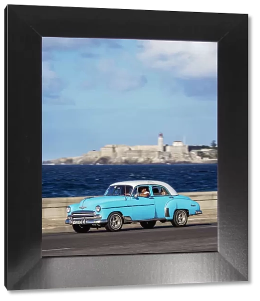 Vintage car at El Malecon with El Morro Castle and Lighthouse in the background, Havana