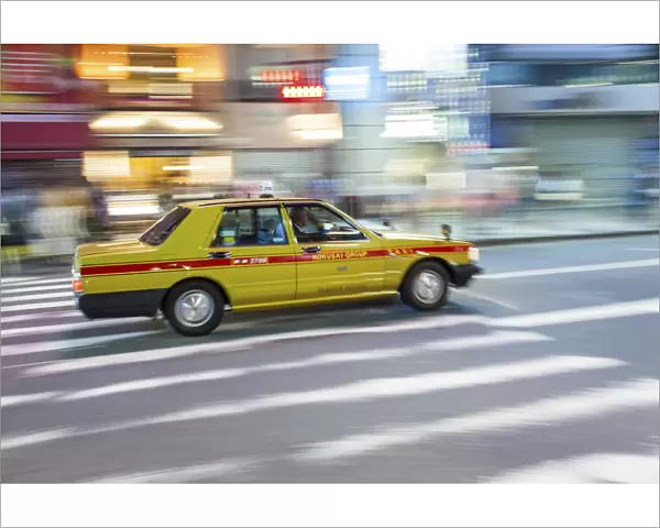 Motion blurred yellow taxi cab on pedestrian crossing, Tokyo, Japan