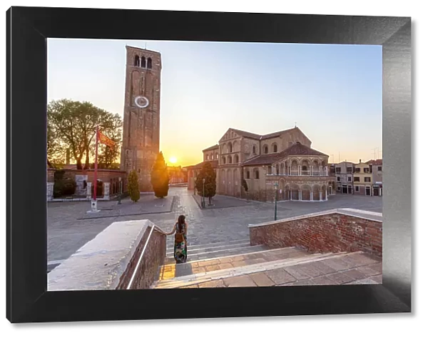 A woman admires the Church of Santa Maria e San Donato (Murano Cathedral) at sunset