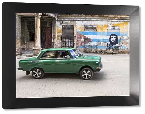 A classic car driving in a front of Che Guevara street art in La Habana Vieja (Old Town)