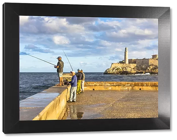 People fishing early in the morning on the Malecon, with Castillo De Los Tres Reyes Del