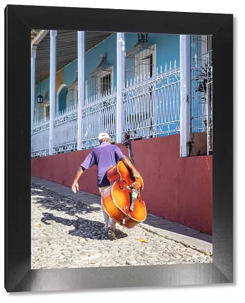 A man carrying a cello in Plaza Mayor in Trinidad, Sancti Spiritus, Cuba