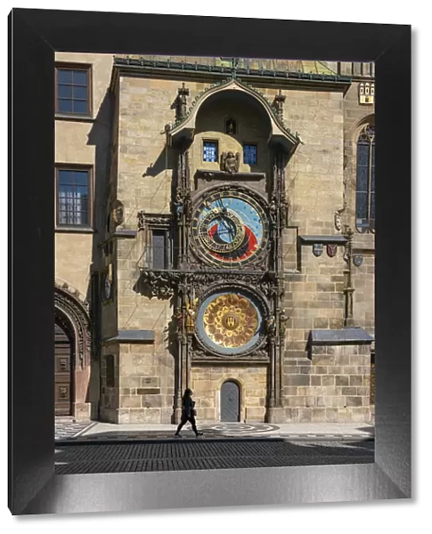 Woman walking by Prague Astronomical Clock at Old Town Square, Prague, Bohemia