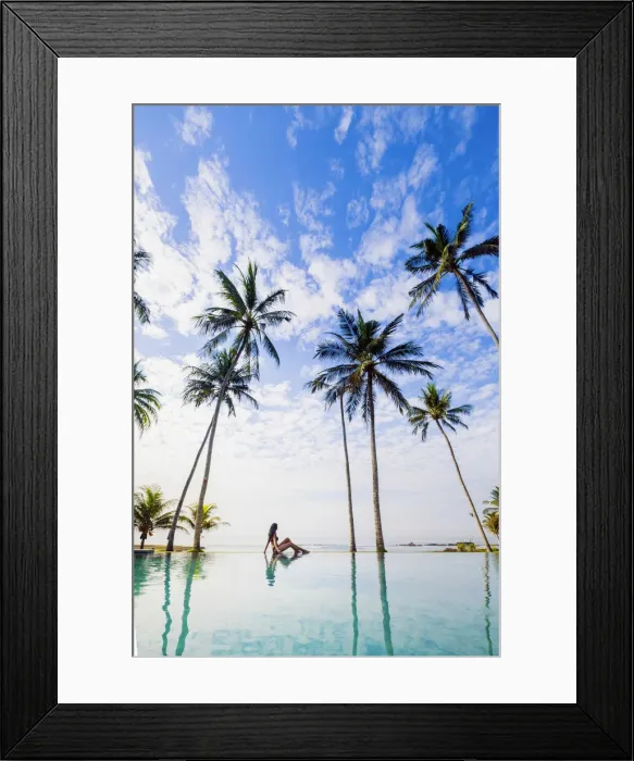 Framed Print : Indonesia, Bali, Candidasa. A young woman sitting on the edge of an infinity swimming Framed Print : Indonesia, Bali, Candidasa. A young woman sitting on the edge of an infinity swimming