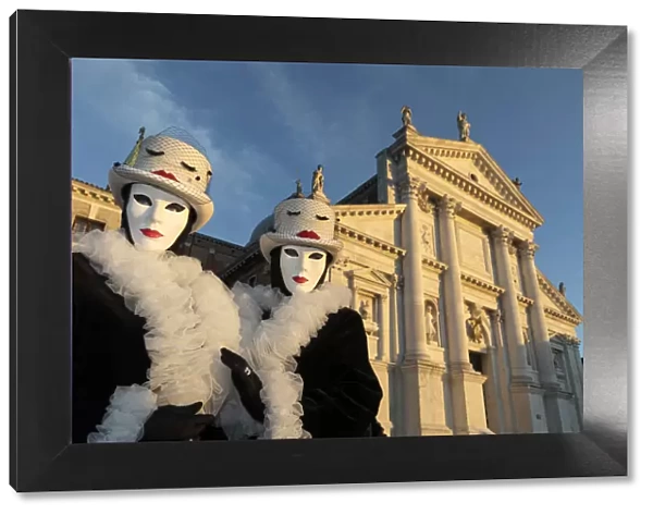 Two women pose in identical costumes during the Venice Carnival, San Giorgio Maggiore