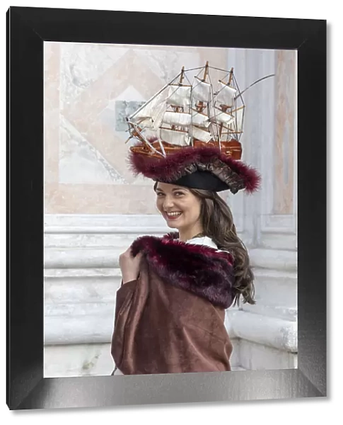 A woman wearing a hat decorated with an old sailing ship poses at the Venice Carnival