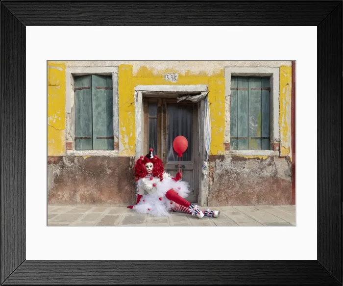 Framed Print : A woman dressed as a clown holds a ballon in front of a colourful facade on Burano Framed Print : A woman dressed as a clown holds a ballon in front of a colourful facade on Burano