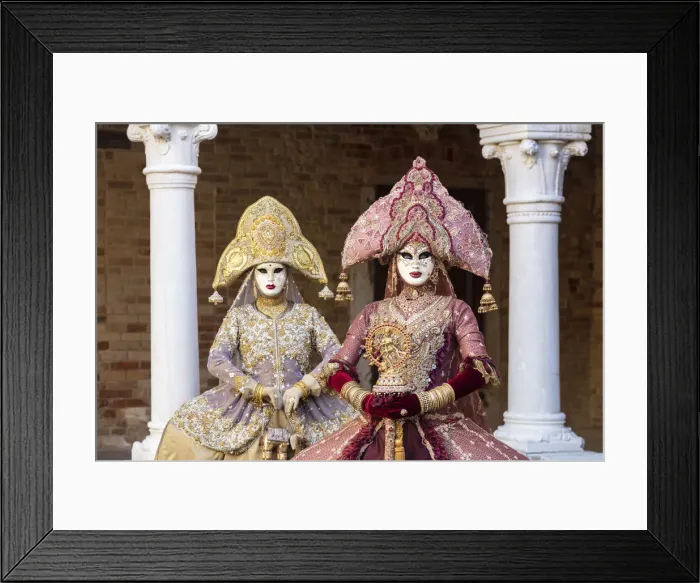 Framed Print : Two women wearing Indian style costumes and masks pose in the cloisters of Chiesa di San Framed Print : Two women wearing Indian style costumes and masks pose in the cloisters of Chiesa di San