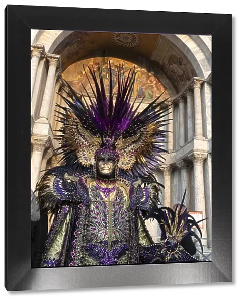 A man in an elaborate costume stands in front of the Basilica Saan Marco in St
