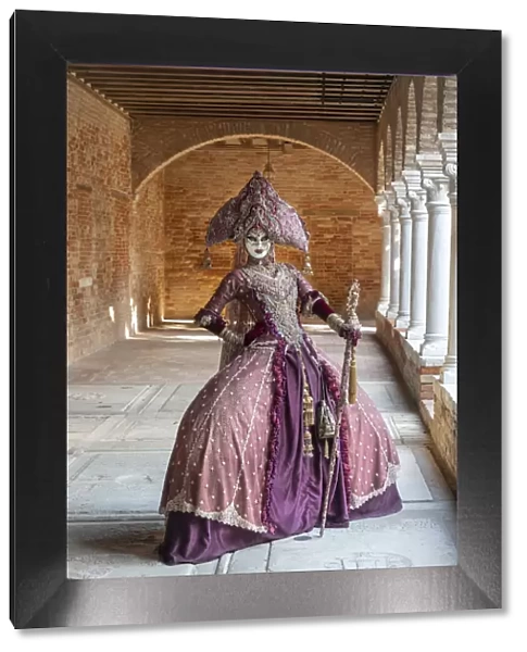 A woman wearing an Indian style costume and mask poses in the cloisters of Chiesa di San