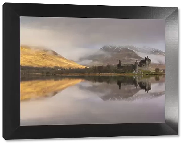The ruins of Kilchurn Castle reflected in Loch Awe at dawn on a misty morning in the