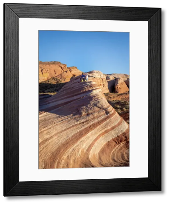 Framed Print : A couple sitting on top of Fire Wave rock formation before sunset Framed Print : A couple sitting on top of Fire Wave rock formation before sunset