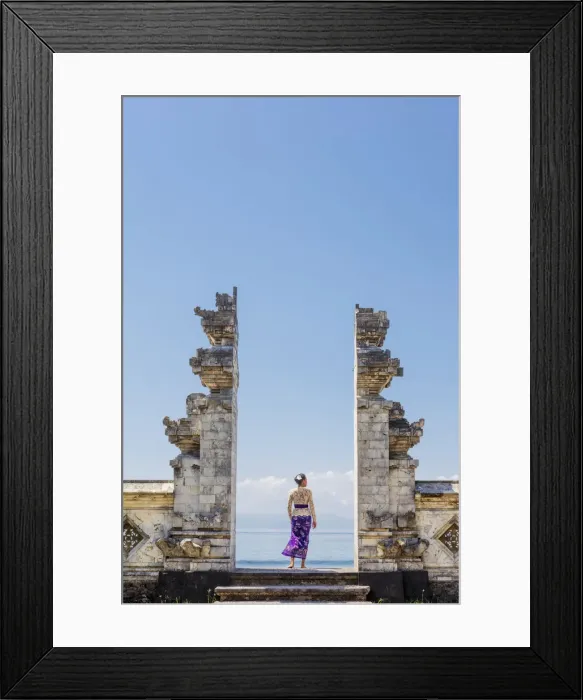 Framed Print : Indonesia, Bali, Candidasa. A local young woman standing in the gateway to the Pura Framed Print : Indonesia, Bali, Candidasa. A local young woman standing in the gateway to the Pura