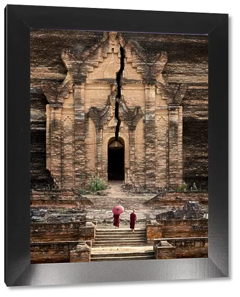 Two novice monks walking towards unfinished Pahtodawgyi pagoda known for a crack caused
