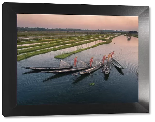 Elevated view of five leg-rowing fishermen rowing on Lake Inle before sunset, Lake Inle
