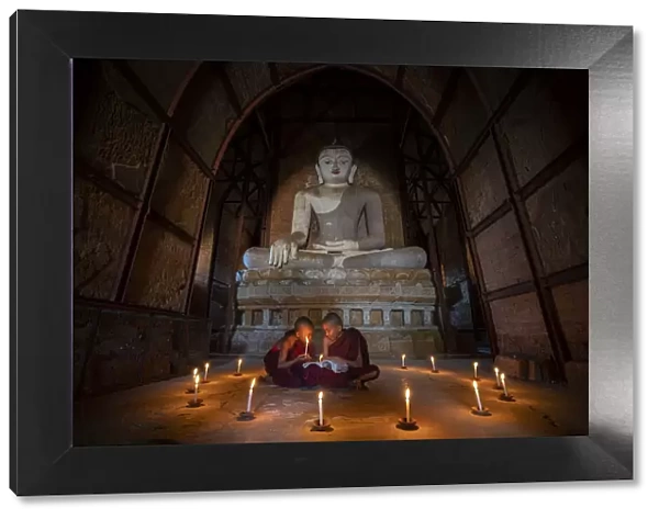 Two novice monks studying inside a temple under big Buddha statue, UNESCO, Bagan