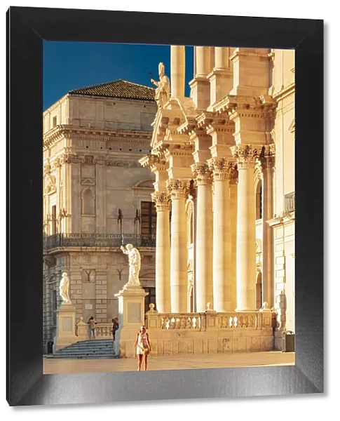 Siracusa, Sicily. A woman walking on the square with the Cathedral in the background at
