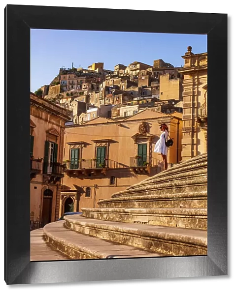 Modica, Sicily. A woman standing on the stairs in front of the baroque Cathedral at