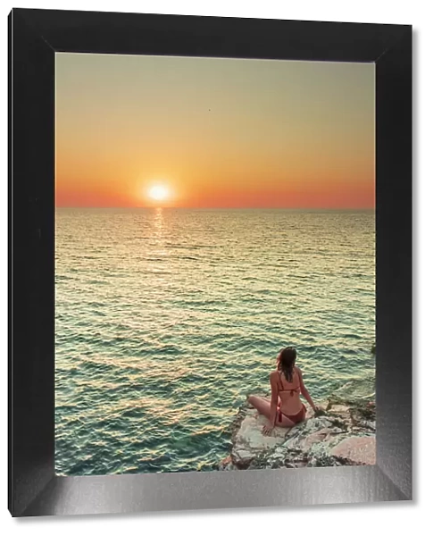 San Vito lo Capo, Sicily. A person enjoying the view of the sun setting along the rock