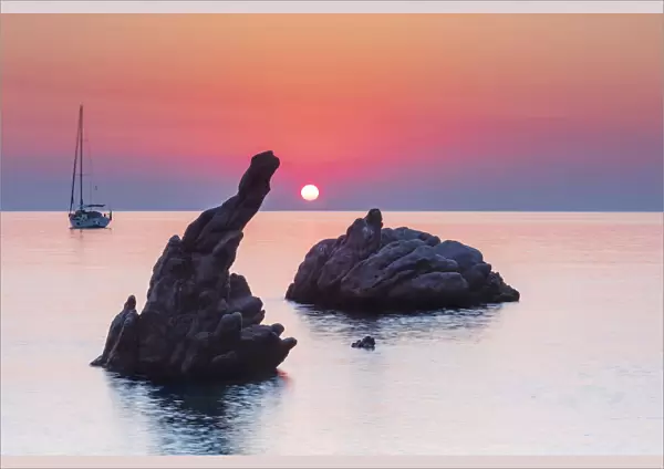 Cefalu, Sicily. Sun rising beyond the rock formations at Kalura beach near Cefalu