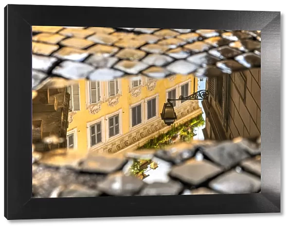 Picturesque corner of the old town reflected in a puddle on a cobbled street, Rome, Lazio