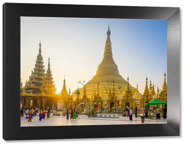 Tourists at gilded Shwedagon Pagoda against clear sky at sunrise, Yangon, Yangon Region