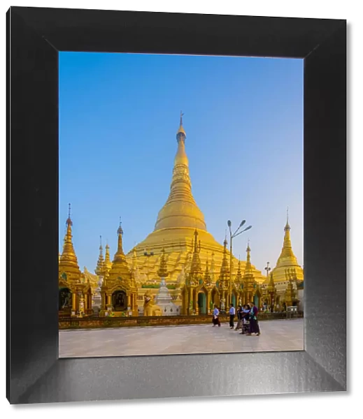 Tourists at gilded Shwedagon Pagoda against clear sky at sunrise, Yangon, Yangon Region