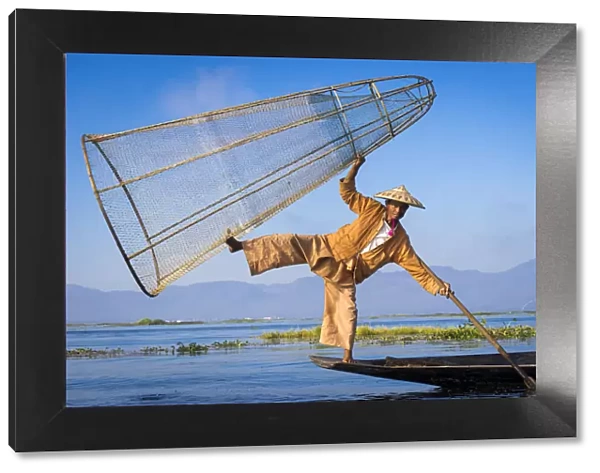 Intha fisherman with a traditional conical fishing net against clear sky, Lake Inle