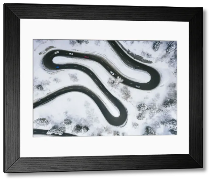 Framed Print : Aerial view of cars driving on narrow bends of mountain road in the snow Framed Print : Aerial view of cars driving on narrow bends of mountain road in the snow