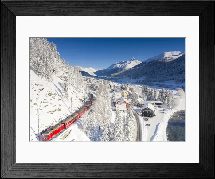 Framed Print : Aerial view of famous red Bernina Express train crossing the snowy village of Madulain Framed Print : Aerial view of famous red Bernina Express train crossing the snowy village of Madulain