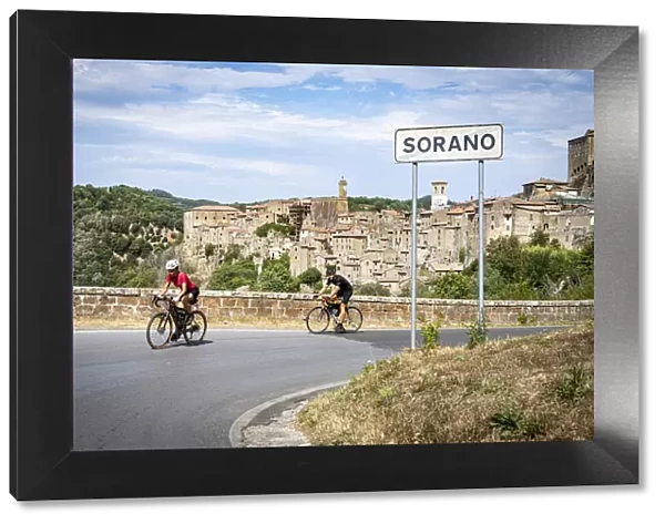 Two cyclist on the road towards the old town of Sorano, province of Grosseto, Tuscany