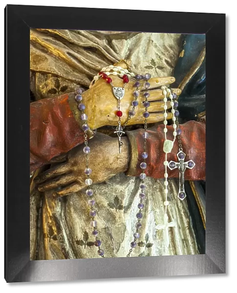 Devotional rosaries in the hands of the wooden statue of Mary. Abruzzo, Italy